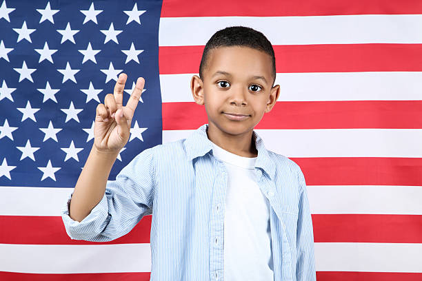 Young student smiling with a peace sign in front of an American flag