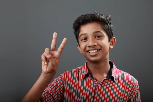Smiling young student in a striped shirt giving a peace sign