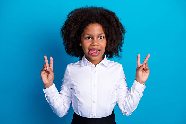 Young student in a white shirt making peace signs on a blue background